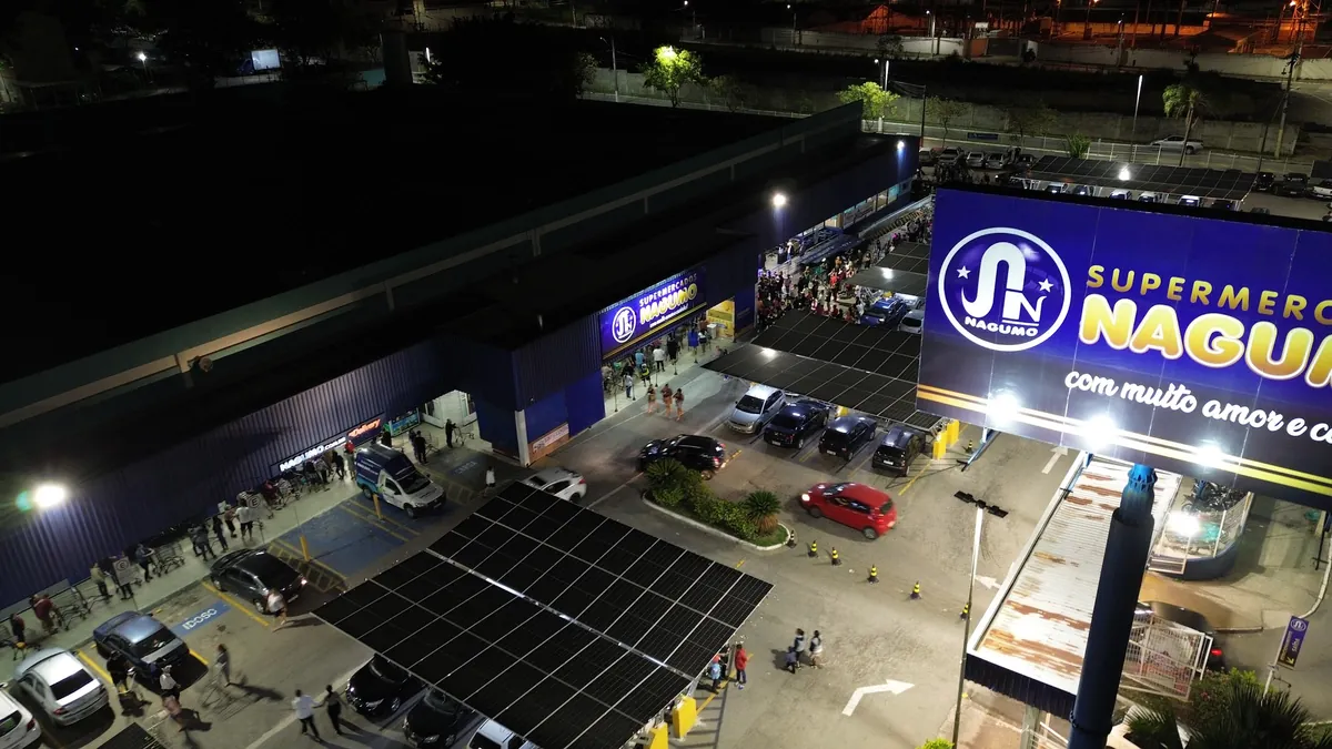 Loja Nagumo à noite vista de drone, com fachada iluminada e estacionamento