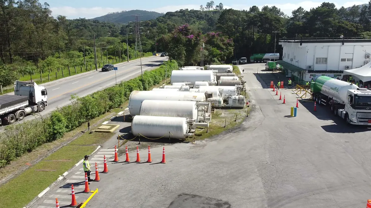 Vista aérea de uma planta industrial de gases, com tanques, caminhões e a rodovia ao lado