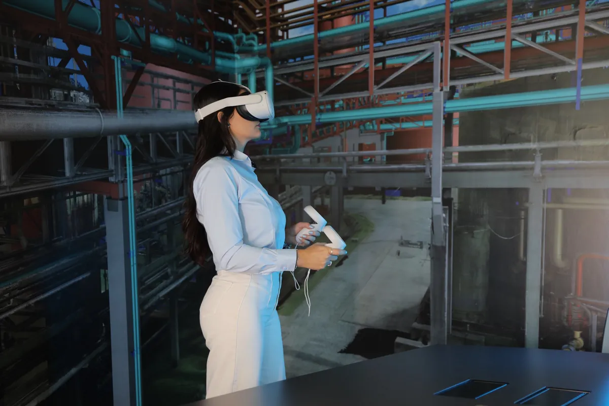 Profissional usando óculos de realidade virtual diante da projeção de uma planta industrial